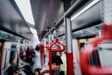 Red hanging handhold for standing passengers in a modern metro train. Suburban and urban transport.