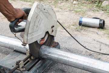Close up of Thai young worker hand using an electric fiber cutting steel bar to cut steel at construction site outdoor.