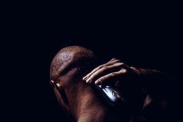 Cut hair and shaves young man on a black background. Close up side portrait of a guy in prison, back view
