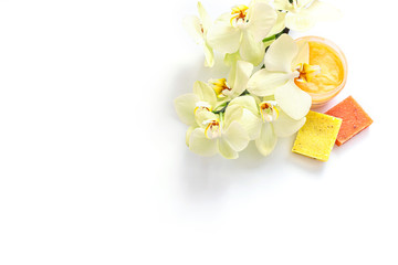Open jar of cosmetic cream, soap and orchid flowers isolated on white background. Concept of organic spa cosmetics. Flat lay, top view, copy space.