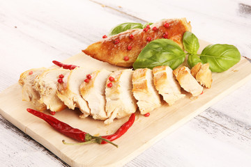 Partially sliced grilled chicken breast on cutting board on table