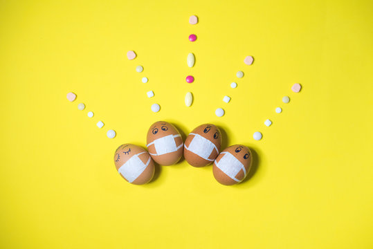 Funny Easter eggs in masks with pills on yellow background. Quarantine. Coronavirus. Isolation.