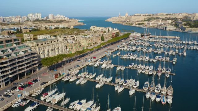 Aerial view of Msida marina, yachts, boats. Sunny day, Valletta city on background. Camera moves forward. Malta island