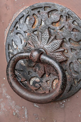 Door knocker. Ancient architecture. Iron fittings on the gate. Entrance to the house. Retro style. Historical building. Antique church. Closed entrance. The decor of the exterior.