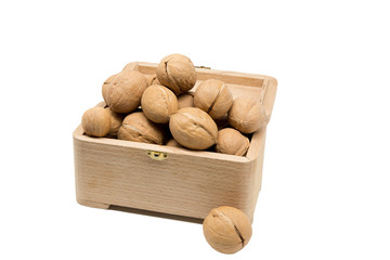 Walnuts slide in a wooden box isolated on white background.