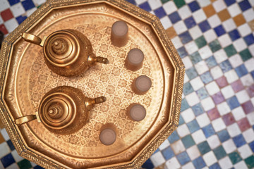 Top view on moroccan brazen tablewear with tiled background.