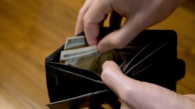 A Man Counts Money Dollars in his Wallet. The Concept of a Dollar Cash in a Crisis. Close - up of the Wallet and Money 