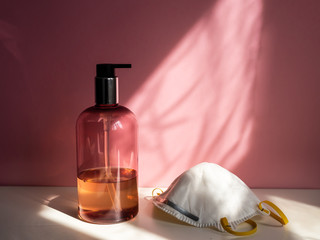 Seifenspender und eine weiße Schutzmaske im Badezimmer, Schattenspiel, rosa Hintergrund, Corona...