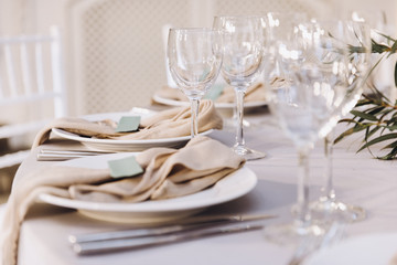 Table setting. On the banquet table there are plates with napkins and name cards, glasses and cutlery