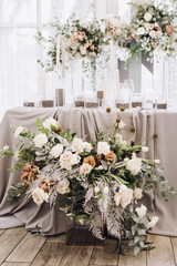 Stylish wedding floristics. Banquet tables decorated with arrangements of flowers, herbs and candles