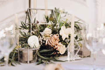 Stylish wedding floristics. Banquet tables decorated with arrangements of flowers, herbs and candles