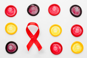 Red ribbon. Top view colorful condoms on white background