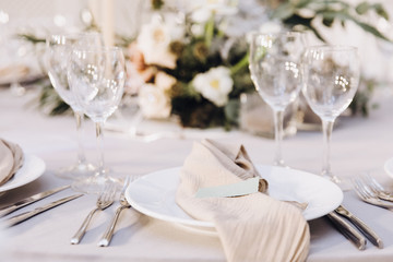 Table setting. On the banquet table there are plates with napkins and name cards, glasses and cutlery