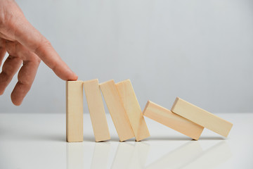Concept of crisis manager from business liquidation. Hand holds wooden blocks on a white background.