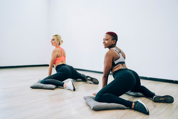 Obraz premium Women enjoying yoga classes while sitting on floor in cat pose