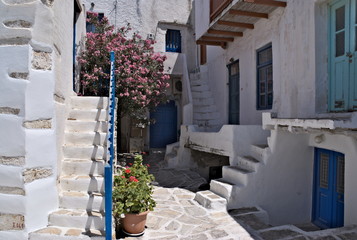 A view of the historic kastro on the Greek island of Antiparos.  Flowers adorn the courtyard, and well worn steps lead up to the old houses that formed part of this Venetian fortification