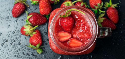 Strawberry smoothies in a transparent glass on a black background.Top view.Banner