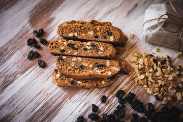 Italian biscotti cookies with walnuts and raisins, shot on a dark wooden background. Background for cooking and home baking.