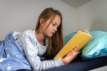 Girl reading book in bed © Markus Wegmann