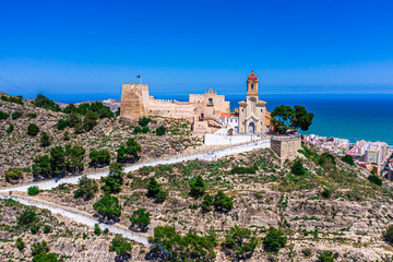 Fototapeta na wymiar Aerial drone photo of a beautiful church/castle aka Castello on top of a mountain in Andalusia Spain in a city called Cullera, with a beautiful background of blue sea 