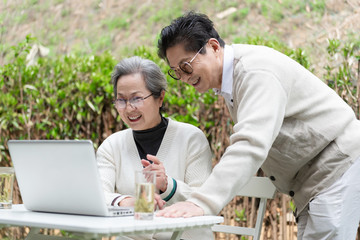 An Asian elderly couple is using a laptop
