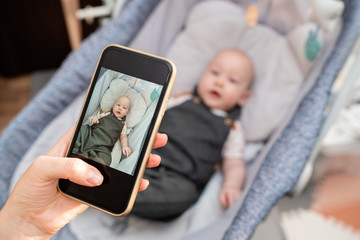 Mother takes a picture with her son by phone. The woman will send photos to grandparents via email....