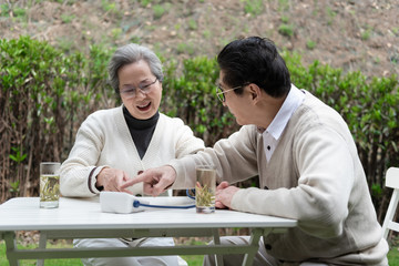 An Asian elderly couple is measuring blood pressure