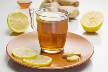 Tea, lemone, fresh ginger root, honey on white background. Close-up.