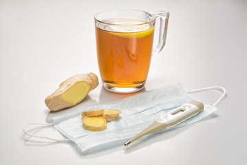 Fresh ginger, tea with lemone, thermometer, medicine face mask on white background