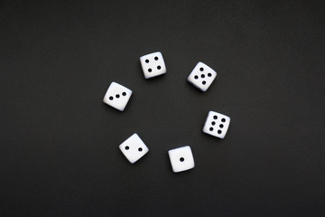 Six white dice placed on a dark metallic surface, copyspace for text.
