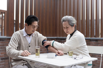 An Asian elderly couple is measuring blood pressure