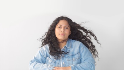 Mixed race plus size woman with natural makeup in studio with long dark wavy hair blowing