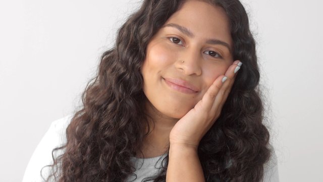 Mixed race native american plus size woman without makeup in studio watching to the camera and touch her face