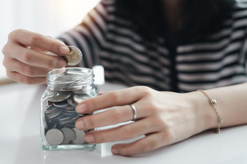 Woman's hand saving a coin for planning, housing and property financial concept