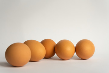 Five fresh brown chicken eggs in a row diagonally on grey background. Easter holiday