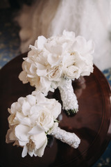 Wedding floristry. Bouquet of white flowers with a white ribbon lies on a wooden table
