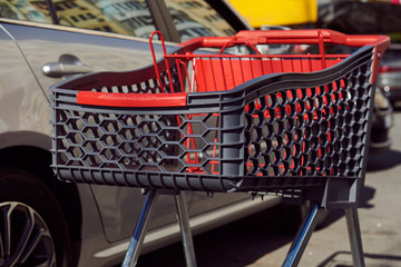Empty shopping cart at the parking between cars on a sunny day. Cart or trolley near the...
