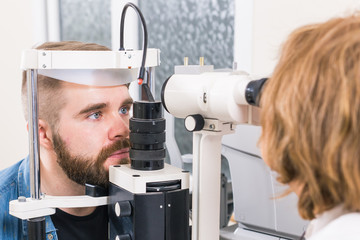 Medicine, health, ophthalmology concept - patient checks her vision by an ophthalmologist.