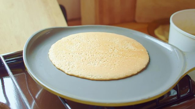 Cook flips delicious bake pancake with spatula in frying pan. Close up. Slowmo.