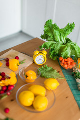 Yellow cooking timer between fresh cooking ingredients - vegetables, lemons and green salad