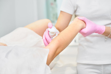Depilation and beauty concept - beautician waxing young woman with liquid sugar at spa. depilation with colored shugaring paste