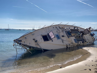 Boat stranded on the beach after a storm. On a sunny day with few clouds. Sailboat