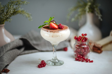 Side view on a sweet appetizing creamy mousse with berries and cacao in a glass on the white background, horizontal