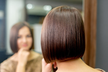 Short hairstyle of woman while looking in the mirror at hair salon.