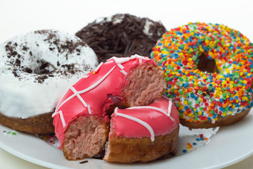 donuts with icing and chocolate in a plate on a white background, close-up