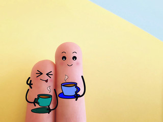 Two fingers are decorated as two person. Both of them are drinking hot coffee.