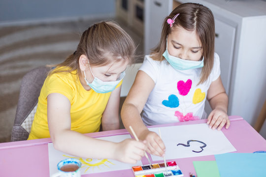 Girls drawing together at home during quarantine in sterile masks. Childhood games, drawing arts, stay at home concept