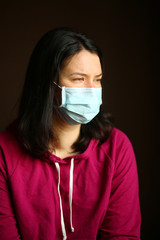 Portrait of a caucasian woman wearing a mask and looking into the window