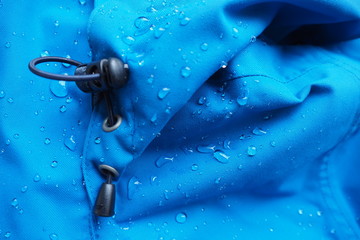 Closeup of water drops on bright blue fabric and elastic band with waterproof design to protect...