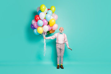 Fototapeta na wymiar Full body photo of amazed excited old man hold many air balloons enjoy festive anniversary party wear pants trousers brown shoes isolated over turquoise color background